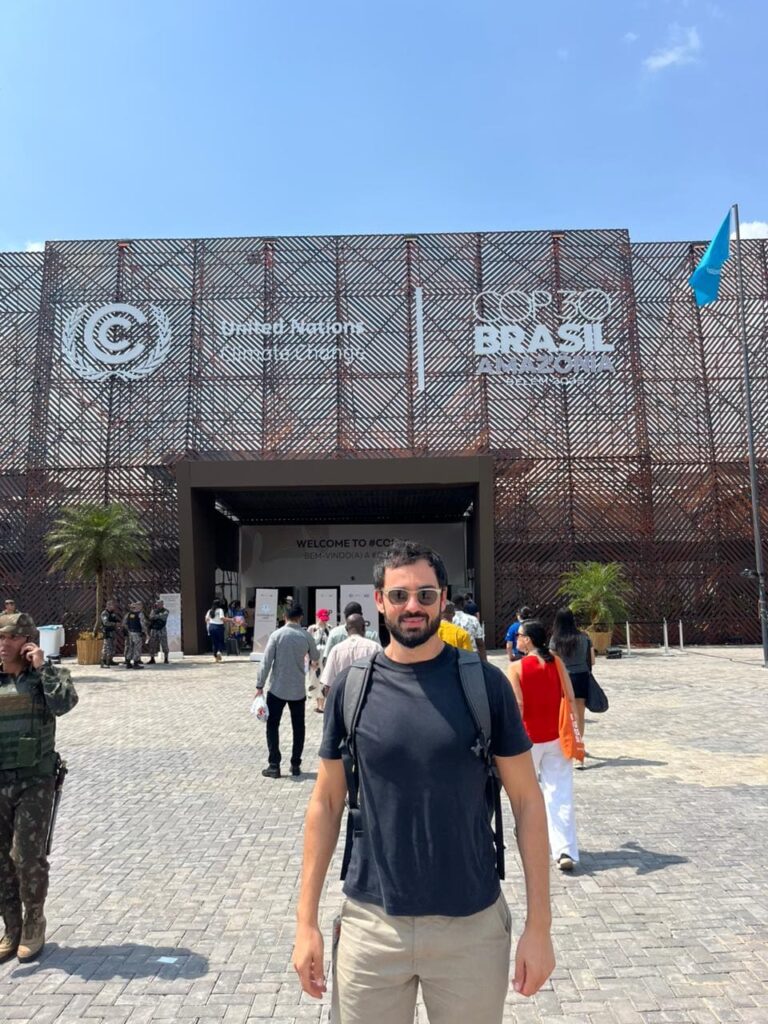 Arthur em frente ao pavilhão da COP30 Brasil Amazônia, com o logotipo das Nações Unidas e da conferência climática ao fundo, durante evento oficial sobre mudanças climáticas